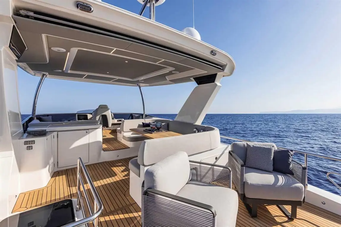 Luxury yacht deck with modern seating, wooden flooring, and a clear blue ocean view under a sunny sky.